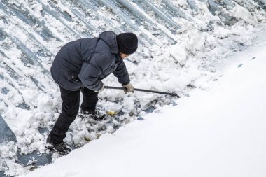 Bir adam kaldırır kar küreği üstten görünüm, metal çatı.
