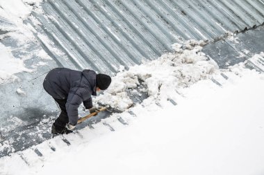 Bir adam kaldırır kar küreği üstten görünüm, metal çatı.
