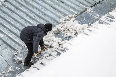 Bir adam kaldırır kar küreği üstten görünüm, metal çatı.