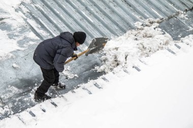 Bir adam kaldırır kar küreği üstten görünüm, metal çatı.