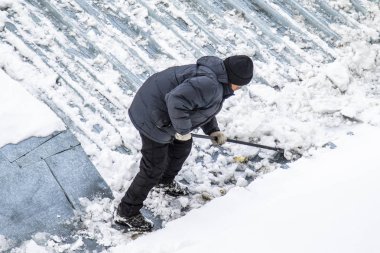 Bir adam kaldırır kar küreği üstten görünüm, metal çatı.