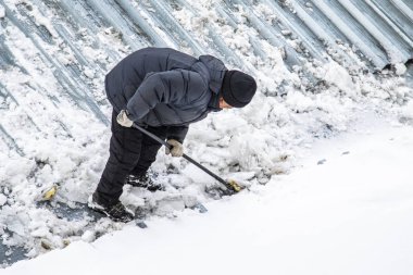 Bir adam kaldırır kar küreği üstten görünüm, metal çatı.