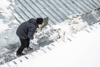 Bir adam kaldırır kar küreği üstten görünüm, metal çatı.
