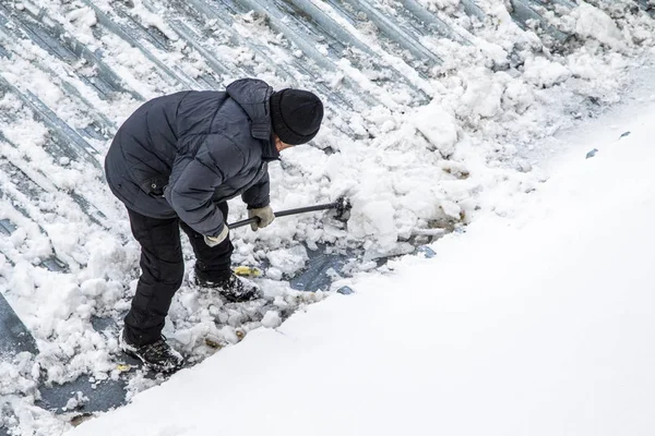 Bir adam kaldırır kar küreği üstten görünüm, metal çatı.