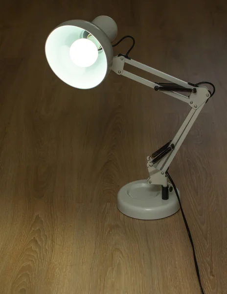 Adjustable desk lamp, wooden table. Studio photo interior closeup.