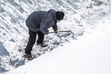 Bir adam kaldırır kar küreği üstten görünüm, metal çatı.