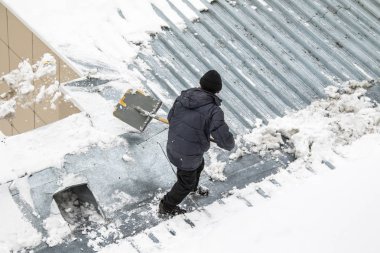 Bir adam kaldırır kar küreği üstten görünüm, metal çatı.