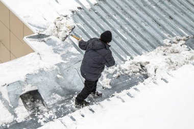 Bir adam kaldırır kar küreği üstten görünüm, metal çatı.