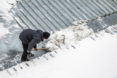 Bir adam kaldırır kar küreği üstten görünüm, metal çatı.