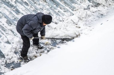 Bir adam kaldırır kar küreği üstten görünüm, metal çatı.