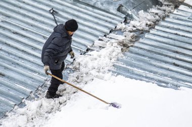 Bir adam kaldırır kar küreği üstten görünüm, metal çatı.