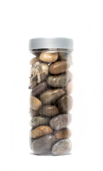 Old transparent jar with different stones on white background
