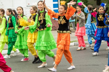 Petropavlovsk, Kazakistan-1 Haziran 2019: Uluslararası Çocuk günü. Şehir sokaklarında okul öğrencileri geçit töreni. Ulusal tatil kıyafetlerinin içinde çocuklar ve ebeveynler. Dans tatil şarkıları.