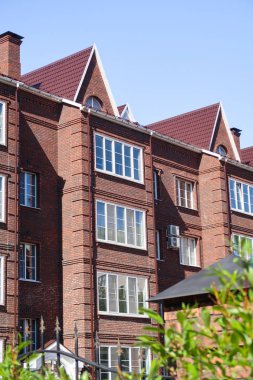 Mavi gökyüzüne karşı çok katlı kırmızı tuğla konut binası. Yaz doğası.