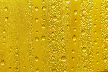 Cam su damlaları, sarı arka plan bira, buğulu arka plan.