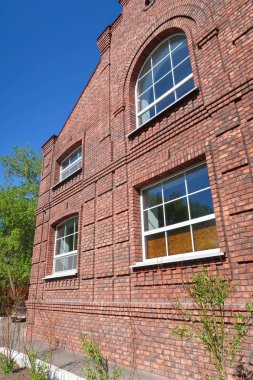 Mavi gökyüzüne karşı çok katlı kırmızı tuğla konut binası. Yaz doğası.