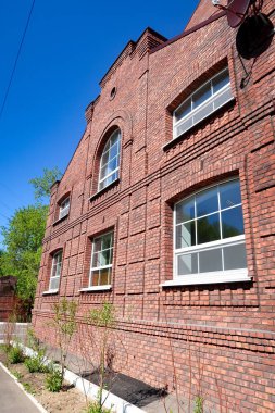 Mavi gökyüzüne karşı çok katlı kırmızı tuğla konut binası. Yaz doğası.