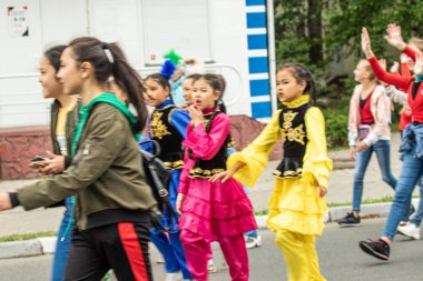 Petropavlovsk, Kazakistan-1 Haziran 2019: Uluslararası Çocuk günü. Şehir sokaklarında okul öğrencileri geçit töreni. Ulusal tatil kıyafetlerinin içinde çocuklar ve ebeveynler. Dans tatil şarkıları.