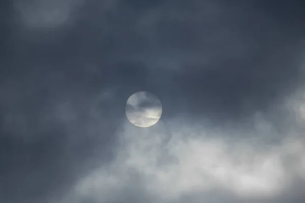 The sun is covered with dark clouds, the sun defocused in the clouds.