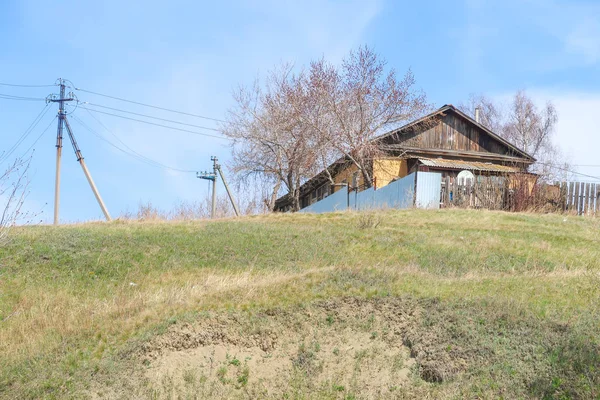 田舎の家は青い空を背景に緑の丘の上に立っている — ストック写真