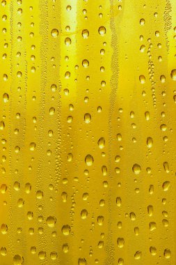 Cam su damlaları, sarı arka plan bira, buğulu arka plan.