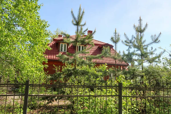 金属フェンスの後ろのレンガ造りの家 春の緑の木公園 — ストック写真