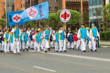 Petropavlovsk, Kazakistan-1 Haziran 2019: Uluslararası Çocuk günü. Şehir sokaklarında okul öğrencileri geçit töreni. Ulusal tatil kıyafetlerinin içinde çocuklar ve ebeveynler. Dans tatil şarkıları.