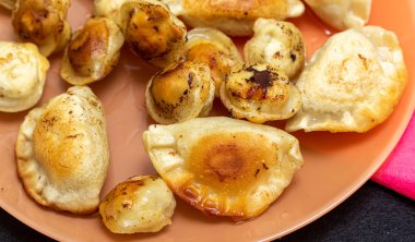 Bir tabakta kızarmış ravioli, kızarmış börek yemek.