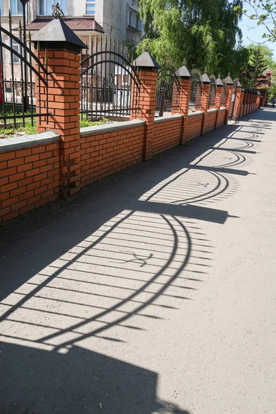 Fém Tégla Kerítés Tükröződik Aszfalt Utcán — Stock Fotó