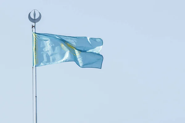 Flag of Kazakhstan against the blue sky.