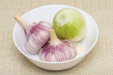 Masada bir tabak içinde soğan ve sarımsak.