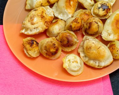 Bir tabakta kızarmış ravioli, kızarmış börek yemek.
