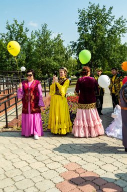 Petropavlovsk, Kazakistan - 17 Ağustos 2019: Çalan ve şarkı söyleyen insanların elinde ki ulusal dombra enstrümanı. Gün tatili, binicilik sütü tatili, içki.