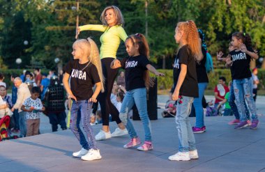 Petropavlovsk, Kazakistan - 23 Ağustos 2019: Çocuklar ve ebeveynler bir şehir parkında dans ediyor. Akşam yaz günü.