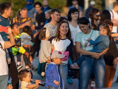 Petropavlovsk, Kazakistan - 23 Ağustos 2019: Anne babalar gece leri şehir parkında yürüyor. Gençler toplu şenlikler geçiriyor.