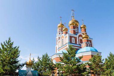 Petropavlovsk, Kazakistan - 20 Ağustos 2019: Gökyüzüne karşı altın kubbeli Ortodoks kilisesi. Doğa, yeşil ağaçlar, manzara.
