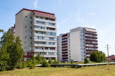 Petropavlovsk, Kazakistan - 20 Ağustos 2019: Mavi gökyüzünün arka planı üzerine yüksek katlı bina, ağaçların yaz manzarası.