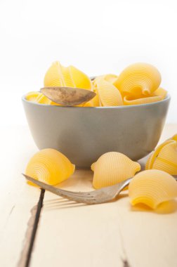 Çiğ İtalyan salyangoz lumaconi makarnası mavi bir kâse üzerinde rustik masa makrosu üzerinde