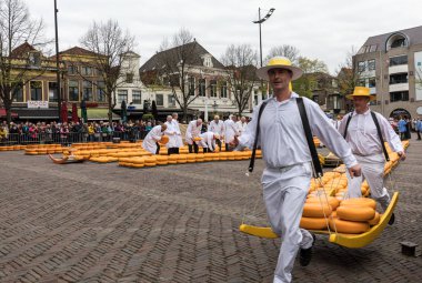 Alkmaar, Hollanda - 21 Nisan 2017: Alkmaar, Hollanda ünlü Hollandalı peynir pazarında birçok peynir ile yürüyüş uçak gemisi. Waagplein Meydanı'nda olay olur. 