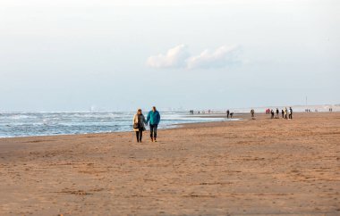 Katwijk, Hollanda - 23 Nisan 2017: Güneşli bir günde Katwijk plaj boyunca insanlar yürüyor. Hollanda