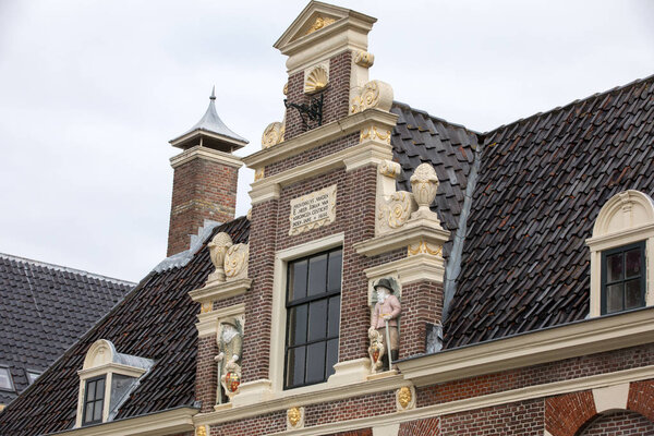 Top gable with memorial stone and sculptures of Huis van Achten in Alkmaar, Netherlands 