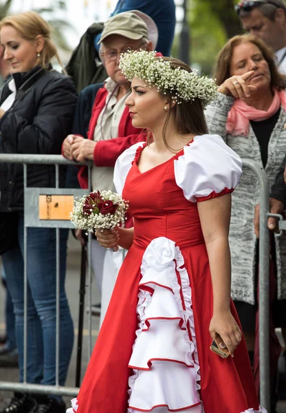 Funchal; Madeira; Portekiz - 22 Nisan; 2018: parade, Kırmızı elbiseli güzel kadınla Madeira çiçek Festivali, Funchal, Madeira, Portekiz, elinde bir buket son anlarıyla