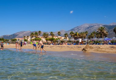 Malia, Girit, Yunanistan - 1 Temmuz 2018: İnsanlar güneşli bir günde Malia, Girit, Yunanistan plajda dinlenme