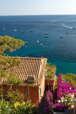 Positano pembe begonviller ve tekne içinde belgili tanımlık geçmiş tarafından çerçeveli. Renkli Positano, Amalfi Coast, rengarenk evleri ve binaları ile mücevheri deniz manzaralı geniş bir tepe üzerinde tünemiş. İtalya