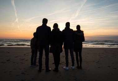 Katwijk, Hollanda - 23 Nisan 2017: Bir grup genç insan Katwijk plajda günbatımında arıyor. Hollanda