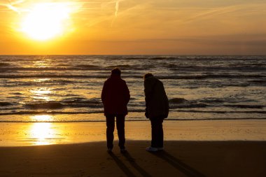Katwijk, Hollanda - 23 Nisan 2017: İki kadın arıyor günbatımında Katwijk plajda. Hollanda
