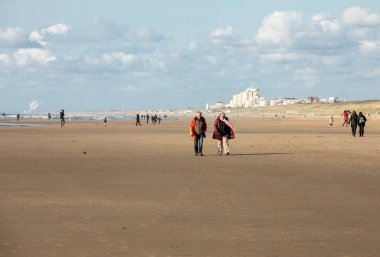Katwijk, Hollanda - 23 Nisan 2017: Güneşli bir günde Katwijk plaj boyunca insanlar yürüyor. Hollanda