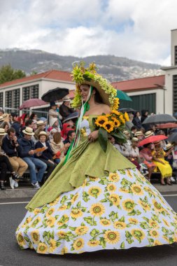 Funchal; Madeira; Portekiz - 22 Nisan; 2018: ayçiçeği motifli renkli elbiseli kadın dans Madeira çiçek Festivali geçit töreninde Funchal, Madeira Adası üzerinde. Portuga