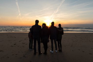 Katwijk, Hollanda - 23 Nisan 2017: Bir grup genç insan Katwijk plajda günbatımında arıyor. Hollanda