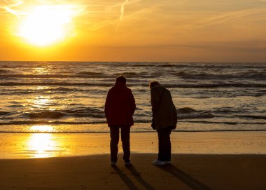 Katwijk, Hollanda - 23 Nisan 2017: İki kadın arıyor günbatımında Katwijk plajda. Hollanda